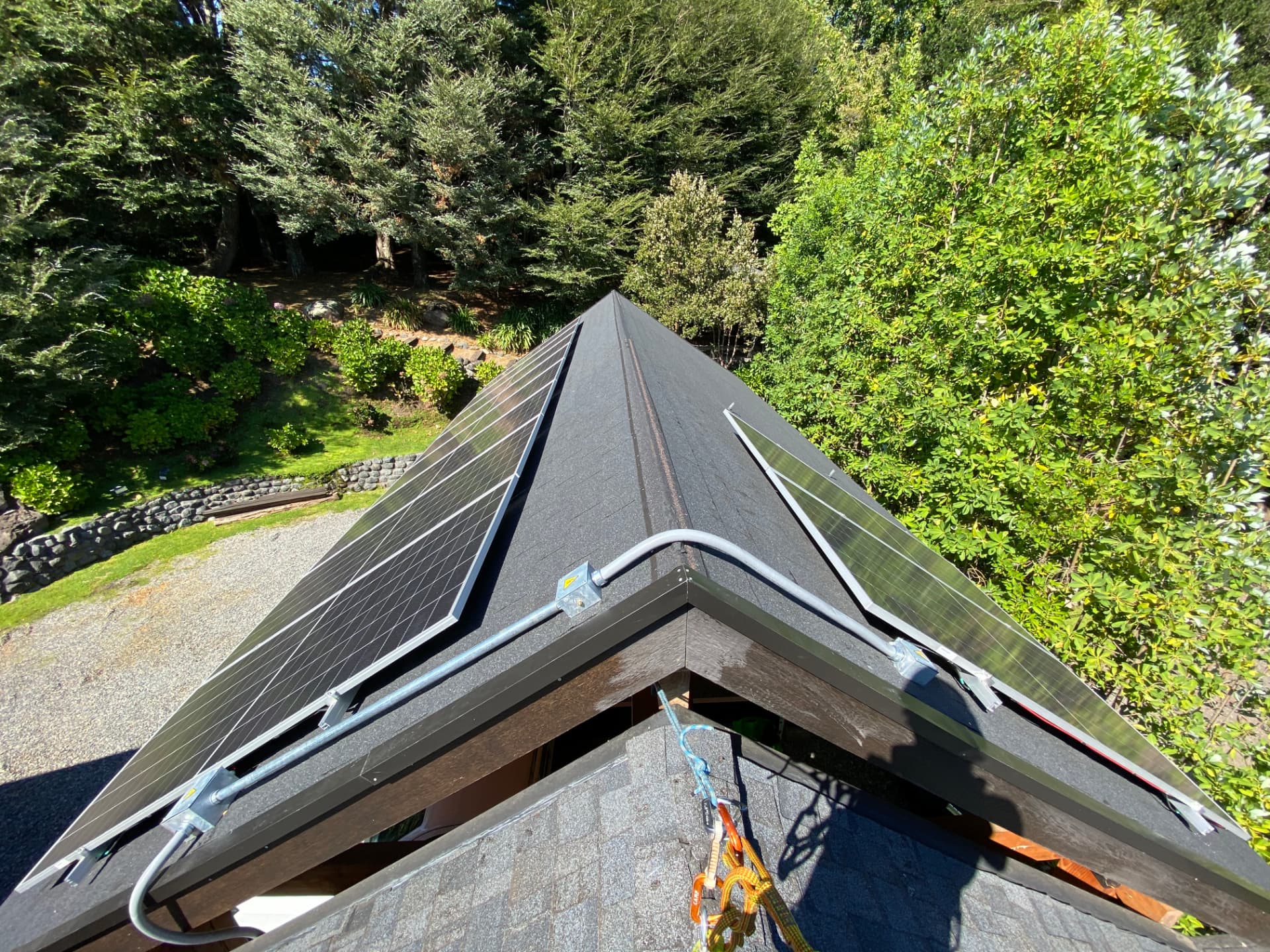 Paneles solares instalados en un techo a dos aguas rodeado de bosque nativo