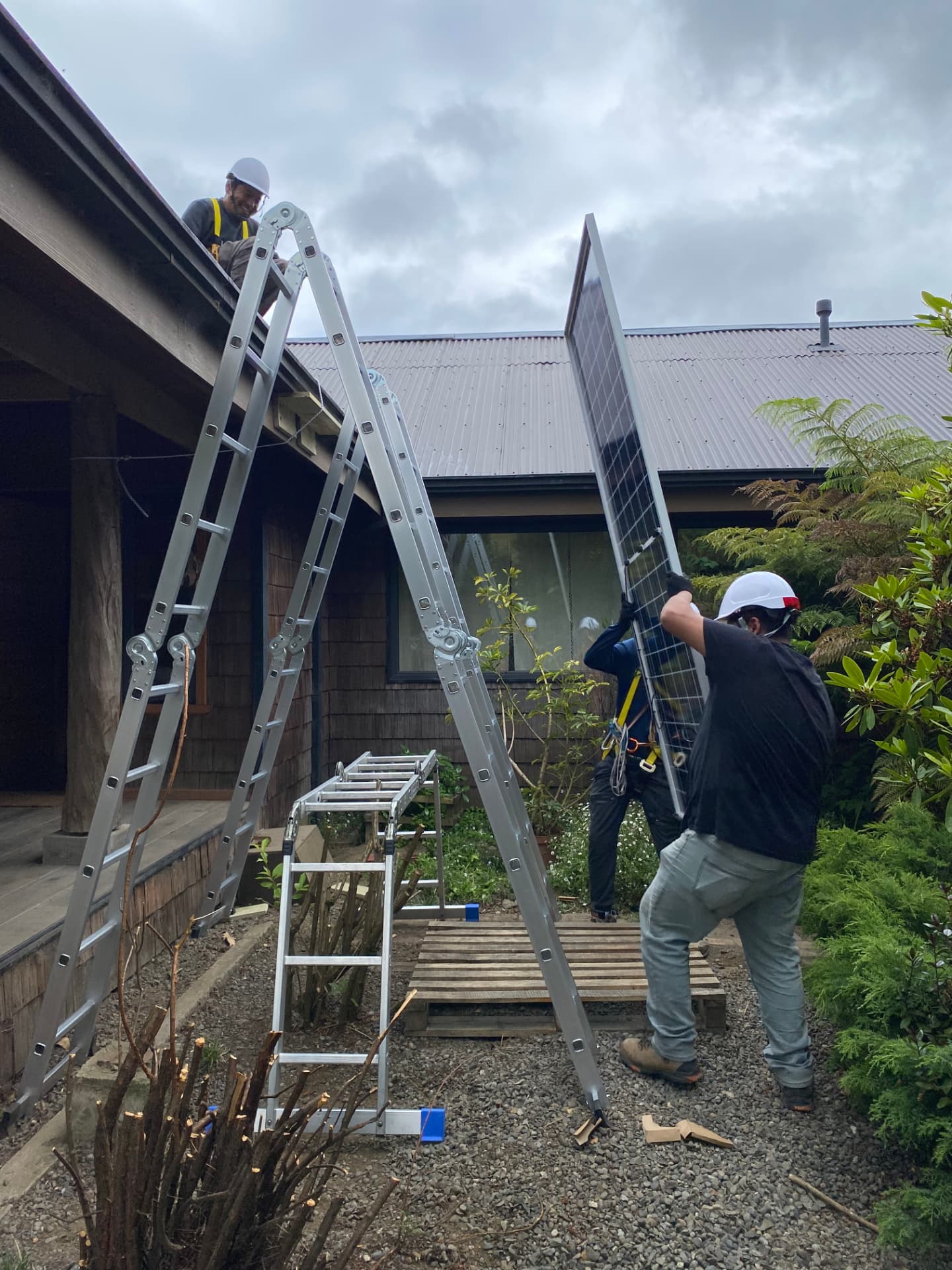 Equipo de Yamakawa subiendo un panel solar al techo de una casa en el sur de Chile