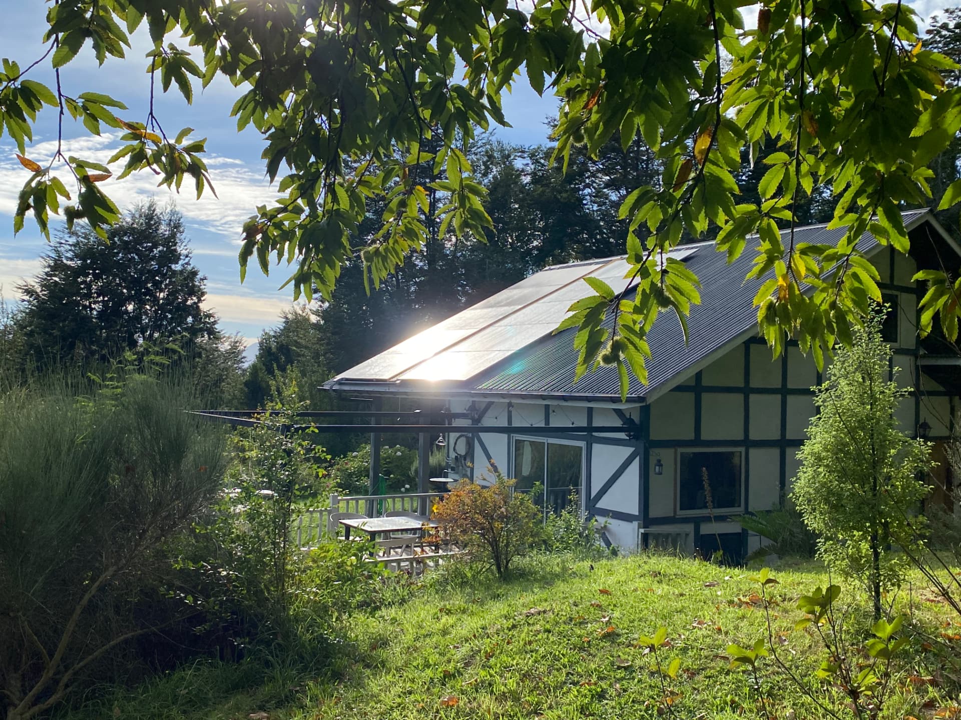 Casa del sur de Chile con paneles solares instalados en el techo, rodeada de vegetación